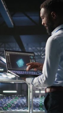 Dikey video sunucusu merkez çalışanları not defteri kullanarak büyük dil model mimarisini görselleştiriyorlar. Veri merkezi teknisyenleri endüstriyel platformda nöral ağ yazılım görevlerinde işbirliği yapıyorlar.