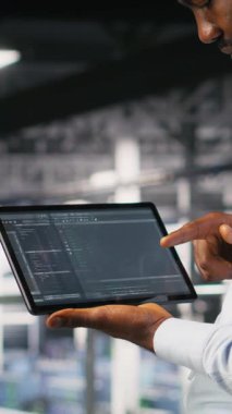 Veritabanında tablet görüntülemede kaydırma yapan programcının dikey videosu, bakım görevleri yapmak, en iyi performansı sağlamak. IT uzmanı aygıt üzerindeki kodu kontrol ediyor, geliştirmek için yamalar uyguluyor