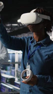 Sanal gerçeklik teknolojisini kullanarak yapay zeka sinirsel ağlarını simüle eden dikey video veri merkezi programcısı. Sunucu çiftliğindeki kadın AI sistemlerini denetlemek için VR kulaklık kullanıyor.