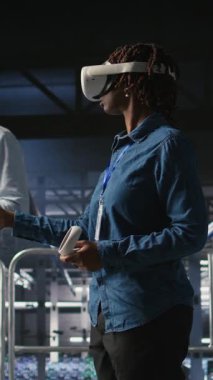 Veri merkezi endüstriyel platformunda sanal gerçeklik teknolojisi kullanarak performans çıktılarını analiz eden dikey video mühendisi. Sunucu merkezi meslektaşları VR kulaklık teknolojisi kullanarak sunucu sondaj ayarlarını inceliyor