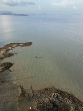 Limanın yakınındaki turkuaz bir körfezdeki tropik yelkenlilerin drone görüntüsü kayalık plajlı Tayland adasının manzaralı sularında yüzen tekneler. Eğlenceli aktivitelerle dolu resimli kıyı şeridi.