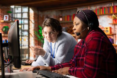 Neşeli çağrı merkezi bilgisayar yazılımının nasıl kullanılacağı konusunda uzman eğitimci. Müşteri destek bürosundaki mutlu yönetici çalışanlara şirket uygulamasının nasıl kullanılacağını gösteriyor