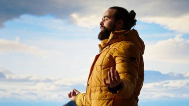 Genç kaşif dağın zirvesine ulaşıyor ve zirvede meditasyon yapıyor, sakin ve dikkatli bir şekilde zen meditasyonu yapıyor. Keyifli yürüyüşçüler doğayı özen gösterdikleri için severler. Kamera B.