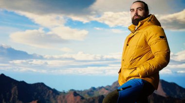 Gezgin, yüksek bir dağ sırasının kenarında tek başına duruyor, bulutlara ve çarpıcı panoramik manzaraya bakıyor. İnsanoğlu kişisel gelişim ve azim gösteriyor. Kamera A.