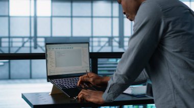 Bilgisayarda veri merkezi kodlaması mühendisi, kaynak kullanımını optimize ediyor, güç yönetimi ayarlarını ayarlıyor. Sunucu odası çalışanı, not defteri ve kamera A kullanarak istikrarlı altyapıyı koruyor.