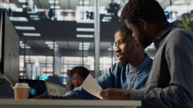 İşletme müdürü, bilgisayar hakkındaki mali tahminleri gözden geçirmek için bir işçiyle birlikte oturuyor ve proje geliştirme hakkında bir analitik değerlendirmeye öncülük ediyor. Gelişim için organizasyonel hedeflere ulaşmak. Kamera A.