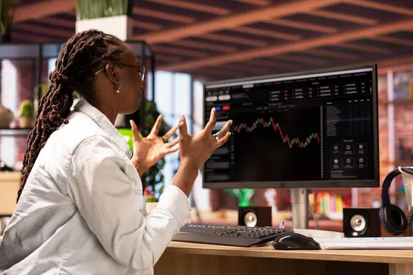 Hüsrana uğramış borsacı üzgün, bilgisayar ekranına bakıyor, düşen hisse senedi fiyatlarını, kırmızı çizelgeleri ve kayıpları gösteriyor. Yatırımcı, monitördeki borsa hisselerinde düşüşe bakarken bunaldı