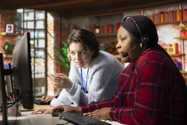 Neşeli çağrı merkezi bilgisayar yazılımının nasıl kullanılacağı konusunda uzman eğitimci. Müşteri destek bürosundaki mutlu yönetici çalışanlara şirket uygulamasının nasıl kullanılacağını gösteriyor