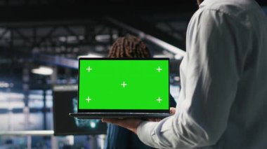 AI LLM görselleştirmesini inceleyen meslektaşının yanındaki yeşil ekran dizüstü bilgisayarı kullanarak sunucu odasını kapat. Yapay zeka sistemlerini, B kamerasını izlemek için veri merkezi IT profesyonel kroma anahtar defteri