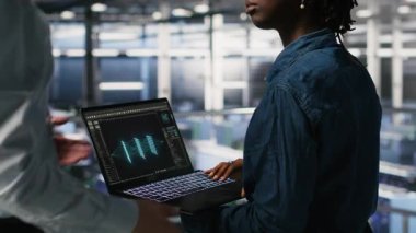 Nöro ağ kodunu ve LLM görselleştirme panellerini inceleyen mühendis tarafından yapılan işi denetleyen sunucu çiftlik yöneticisi. Ekip lideri AI sistem performansını izleyen işçi denetleme, kamera B