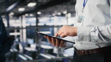 Sunucu odası çalışanının AI LLM görselleştirmesini inceleyen meslektaşının yanındaki tablet üzerindeki kodu kontrol etmesini kapat. Yapay zeka sistemlerini izlemek için aygıt kullanan veri merkezi bilişim uzmanı, kamera B