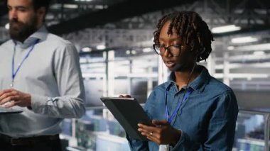 Sunucu odası yönetimi, altyapı teknik desteği sağlamak için tablet ve kulaklık mikrofonu kullanıyor. Veri merkezi bilişim uzmanı uzak ekipler, kamera B ile koordine ederken arka uç sorunlarını çözer