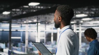 Veri merkezi programcısı kod satırlarını kontrol ediyor ve iş arkadaşı AI LLM görselleştirmelerini inceliyor. IT uzmanları, tablet kullanarak istikrarlı altyapı işlemleri sağlamak için nöral ağ çıktılarını analiz ederler