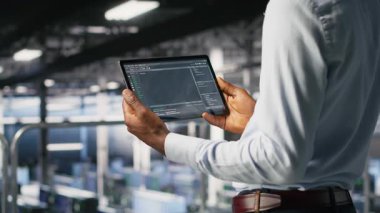 Veri merkezi yönetimi tablet üzerindeki kodu, bulanık arkaplandaki yapay zeka görüntülerini inceleyen meslektaşın yanında kontrol ediyor. Bilişim uzmanları sinirsel ağ çıktılarını analiz etmek ve istikrarlı dişli işlemleri sağlamak için aygıt kullanırlar