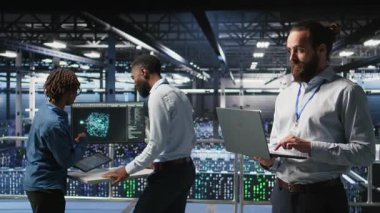 Bilgisayar bilimcileri veri merkezi endüstriyel platformunda dizüstü bilgisayardaki performans çıktılarını analiz ediyorlar. Sunucu çiftliği bilişim uzmanları ince donanım yapılandırmaları, kamera A üzerinde işbirliği yapıyorlar.