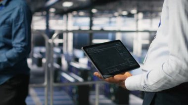 Makine öğrenme kod gösterge panellerini incelemek için tablet kullanarak veri merkezi yönetimini kapat. Yapay zeka altyapı performansını izlemek için aygıt kullanan sunucu çiftliği bilişim uzmanı, kamera B