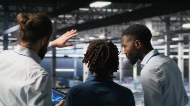 Veri merkezi yöneticisi, yapay zeka için kullanılan süper bilgisayarların bakımını yapan işçilerle konuşuyor. Sunucu merkezi ekip lideri ve personel üyeleri derin öğrenme eğitimi için kullanılan platformları güncelliyor, kamera B