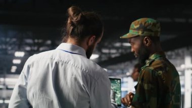 Askeri teknisyen güvenli sunucu merkezinde dizüstü bilgisayardaki taktik gösterge panelini inceliyor. Not defterinde stratejik iletişim ve altyapı denetim yazılımı kullanan ordu uzmanı, kamera B