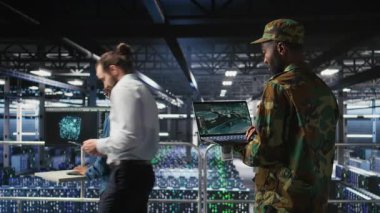 Sunucu odasındaki asker acil operasyonlar sırasında tahliye için coğrafi verileri kullanıyor. Felaket müdahale lojistiğini dizüstü bilgisayar ve kamera A kullanarak koordine eden üniformalı askeri veri merkezi personeli.