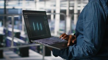 Veri merkezindeki yönetimi nöral ağ LLM görüntülemesini izlemek için dizüstü bilgisayar kullanarak kapat. Sunucu merkezi bilişim uzmanı teçhizata güç veren makine öğrenme süreçlerini not defteri, kamera B kullanarak denetliyor