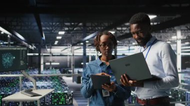 Veri merkezi sistem yöneticileri AI LLM görselleştirmelerini gözden geçirmek için dizüstü bilgisayar kullanıyorlar. Afrika kökenli Amerikan bilişim uzmanları sinirsel ağların çıktılarını analiz etmek için aygıt kullanırlar.