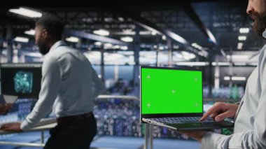 Veri merkezi çalışanlarının yeşil ekran dizüstü bilgisayarında bakım görevleri yaparak optimal performansı güvence altına almalarını sağla. İşçi, tanıları gözden geçirmek ve yamaları uygulamak için maket defteri kullanır, kamera A