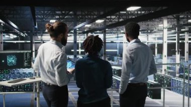 Veri merkezi yöneticisi, yapay zeka için kullanılan süper bilgisayarların bakımını yapan işçilerle konuşuyor. Sunucu merkezi ekip lideri ve personel üyeleri derin öğrenme eğitimi için kullanılan platformları güncelliyor, kamera A