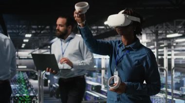 Veri merkezi programcısı sanal gerçeklik teknolojisini kullanarak yapay zeka sinirsel ağlarını taklit ediyor. Sunucu çiftliğindeki kadın AI sistemlerini denetlemek için VR kulaklık kullanıyor. Kamera A.