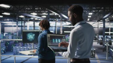 Veri merkezindeki mühendis ve meslektaşım dizüstü bilgisayardaki büyük dil modeli görselleştirmelerini inceliyor. Bilişim mühendisliği ekibi, istikrarlı altyapı işlemleri için sinirsel ağ performans çıktılarını analiz ediyor