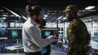 Yüksek teknoloji sunucu tesisinde yapay zeka işlemlerini askeri personel denetliyor. Ordu teknoloji uzmanları iletişim sistemlerini ve kamera A 'yı denetlemek için yapay zeka kullanıyor.