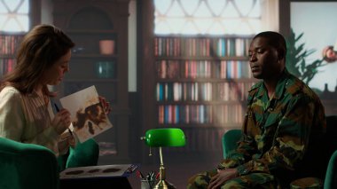 Kadın terapist, danışmanlık oturumunda silahlı kuvvetler üniformalı siyah bir askere Rorschach mürekkep lekesi testi sunuyor. Kitap raflarıyla dolu sıcak bir ofiste terapi gören farklı insanlar. Kamera B.