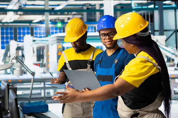 Dizüstü bilgisayardaki güneş panellerini karşılaştıran tüm siyah mühendisler imalat fabrikasındaki üretim hattı üzerinde çalışıyor. En iyi hale getirmek için hata ayıklama ve hata ayıklama.