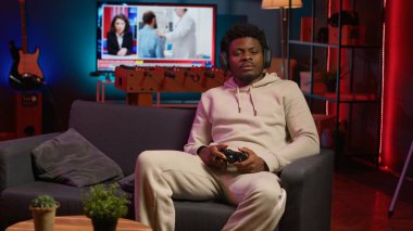 Evde oturan oyuncu boş zamanlarında dizüstü bilgisayarında oyunların keyfini çıkarıyor. Oturma odasında kanepede oturan siyah adam, bilgisayar oyunu oynuyor, işten sonra dinleniyor. Kamera A.