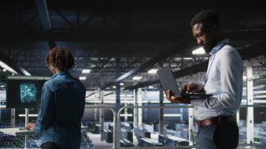 Veri merkezindeki gülen teknisyen ve meslektaşım bilgisayardaki büyük dil modeli görselleştirmelerini inceliyor. Mutlu bilişim mühendisliği ekibi sinirsel ağ performans çıktılarını analiz ediyor