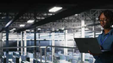 Veri Merkezi bilgisayar bilimcisi laptopta bakım görevleri yapıyor ve en iyi performansı sağlıyor. Afrikalı Amerikalı teknisyen tanıları inceliyor ve sunucu merkezi ekipmanına yama uyguluyor, kamera B