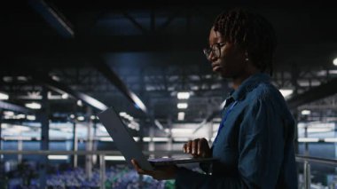 Veri Merkezi bilgisayar bilimcisi laptopta bakım görevleri yapıyor ve en iyi performansı sağlıyor. Afrika kökenli Amerikalı teknisyen tanıları inceliyor ve sunucu merkezindeki kamera A 'ya yama uyguluyor.