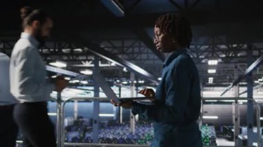 Sunucu çiftliğindeki veri bilimci sinirsel ağ kodunu ve LLM görselleştirme panelini inceliyor. Bilgi işlem uzmanı endüstriyel platformda yürüyor, yapay zeka sistemi performansını izliyor, kamera A