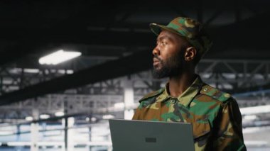 Ordu bilgi teknolojisi uzmanı. Bilgisayar kullanarak askeri bilgisayar sistemlerinde ve ağlarda sorun çıkarıyor. Komuta Merkezi sunucu odasında not defteri, kamera B kullanarak asker