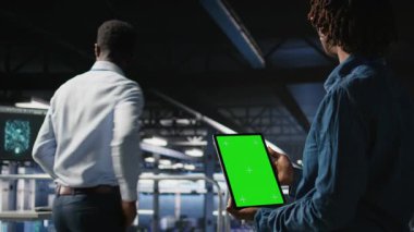 Veri merkezi mühendisleri yeşil ekran tableti kullanarak sinirsel ağ LLM görselleştirmesini izliyorlar. Sunucu çiftliği bilişim uzmanları, krom anahtar aygıtı, kamera A kullanarak güç veren makine öğrenme süreçlerini denetliyor.