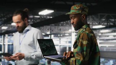 Veri merkezindeki askeri teknisyen bilgisayardaki uzaktan kumandalı savaş uçağı ölçümlerini izliyor. Ordu sunucu odasında bilişim uzmanı. Hava operasyonlarını desteklemek için taktik arayüzü kullanıyor. Kamera B.