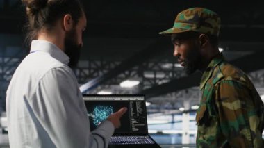 Yüksek teknoloji sunucu tesisinde yapay zeka işlemlerini askeri personel denetliyor. Ordu teknoloji uzmanları iletişim sistemlerini denetlemek için yapay zeka kullanıyor, kamera B