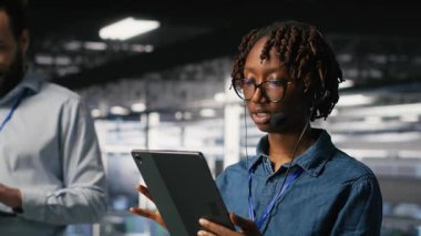 Veri merkezi mühendisi kulaklık takarak tablet kullanarak uzaktan tanı koyuyor. Teknisyen sistem sağlığını izliyor ve kullanıcılara altyapı sorun çözme adımları, kamera B yoluyla rehberlik ediyor