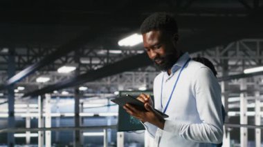 Veri Merkezi Endüstriyel Platformu yöneticisi tabletteki altyapı performans çıktılarını analiz ediyor. Sunucu odası çalışanı iş görevleri yapıyor, ana bilgisayarları inceliyor, yapılandırmalar, kamera B