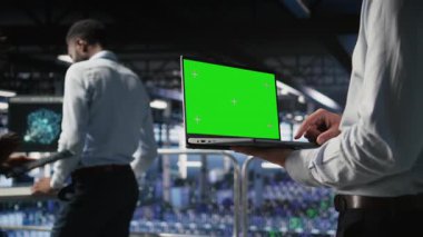 AI LLM görselleştirmesini inceleyen meslektaşının yanındaki yeşil ekran dizüstü bilgisayarı kullanarak sunucu odasını kapat. Yapay zeka sistemlerini, kamera A 'yı izlemek için veri merkezi IT profesyonel kroma anahtar defteri