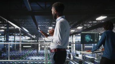 Veri Merkezi Endüstriyel Platformu yöneticisi tabletteki altyapı performans çıktılarını analiz ediyor. Sunucu odası çalışanı iş görevleri yapıyor, ana bilgisayarların ayarlarını ayarlıyor, kamera A