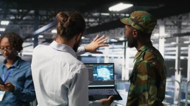 Güvenli veri merkezindeki askeri teknisyenler yapay zeka sistemlerini izlemek için dizüstü bilgisayar kullanıyorlar. Ordu operatörleri sunucu merkezinde makine öğrenme işlemleri için istikrarlı altyapı sağlıyorlar, kamera B