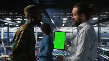 Yüksek teknoloji sunucu tesislerindeki izole ekran tabletindeki yapay zeka işlemlerini askeri personel denetliyor. Ordu teknoloji uzmanları iletişim sistemlerini denetlemek için kroma anahtar aygıtı kullanıyorlar. Kamera A.