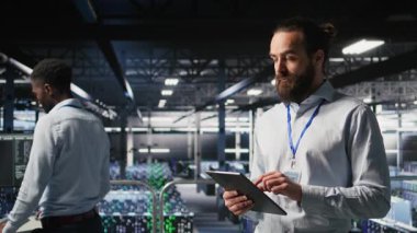 Neşeli veri merkezi idarecisi tablet üzerinde bakım görevleri yapıyor ve en iyi performansı sağlıyor. Bilgi İşlem uzmanı tanıları gözden geçiriyor ve sunucu merkezi dişlisine yama uyguluyor, kamera A