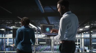 Sunucu merkezi çalışanları not defteri kullanarak büyük bir dil modeli mimarisi görselleştiriyorlar. Sanayi platformundaki veri merkezi teknisyenleri dizüstü bilgisayar kullanarak nöral ağ yazılım görevlerinde işbirliği yapıyorlar