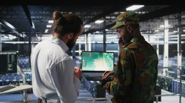 Askeri veri merkezindeki İHA operatörleri dizüstü bilgisayar arayüzü ile otonom uçuş sistemlerini denetliyor. Ekip çalışması bilişim uzmanları canlı İHA takibi yapıyorlar. Not defteri, kamera A kullanarak.